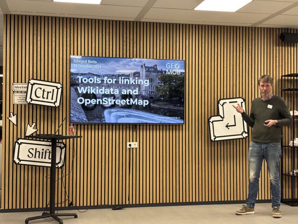 A man presenting beside a screen