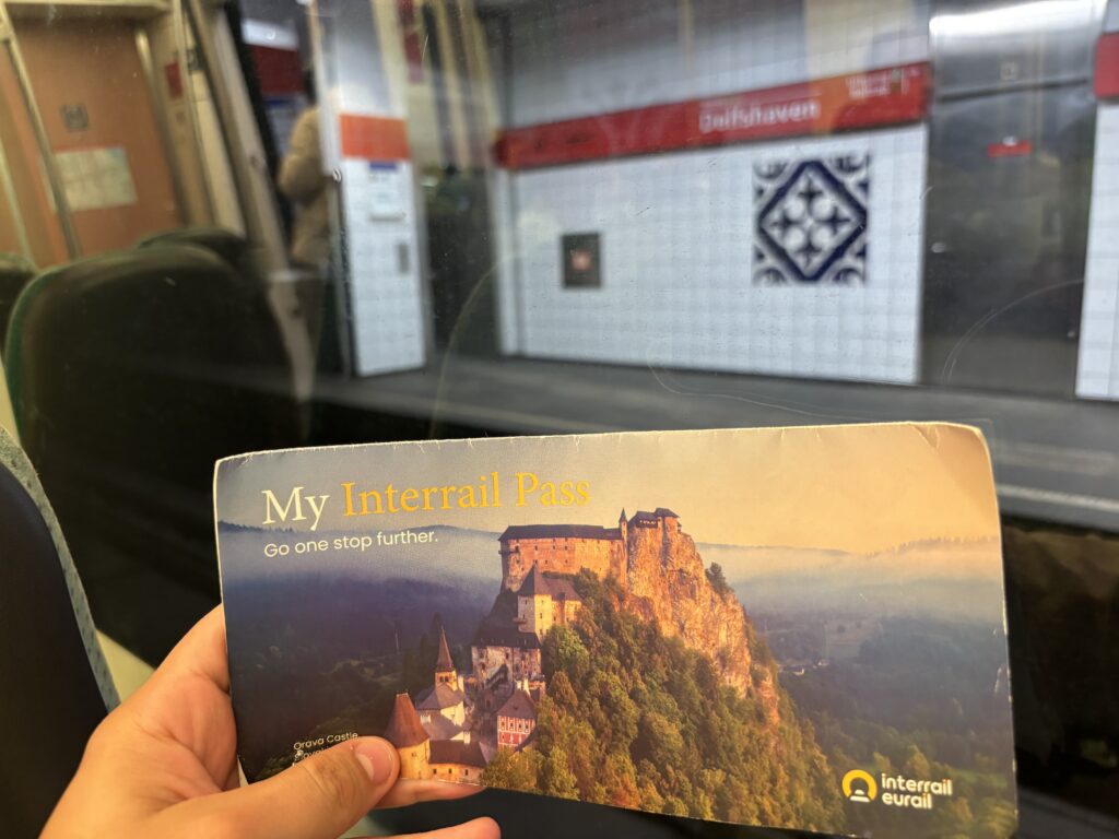 Displaying the Interrail pass onboard a metro train. On the background, across the window, a metro platform can be seen.