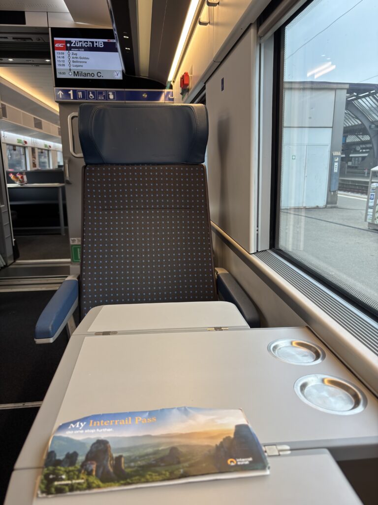 A table seat in a single seat configuration. The table has an Interrail ticket on it.